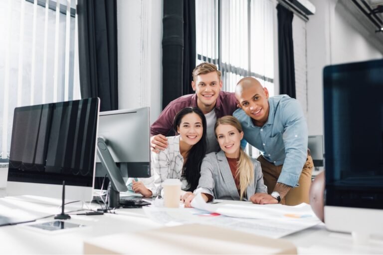 Smiling diverse team of office professionals collaborating together at a desk in a modern workplace