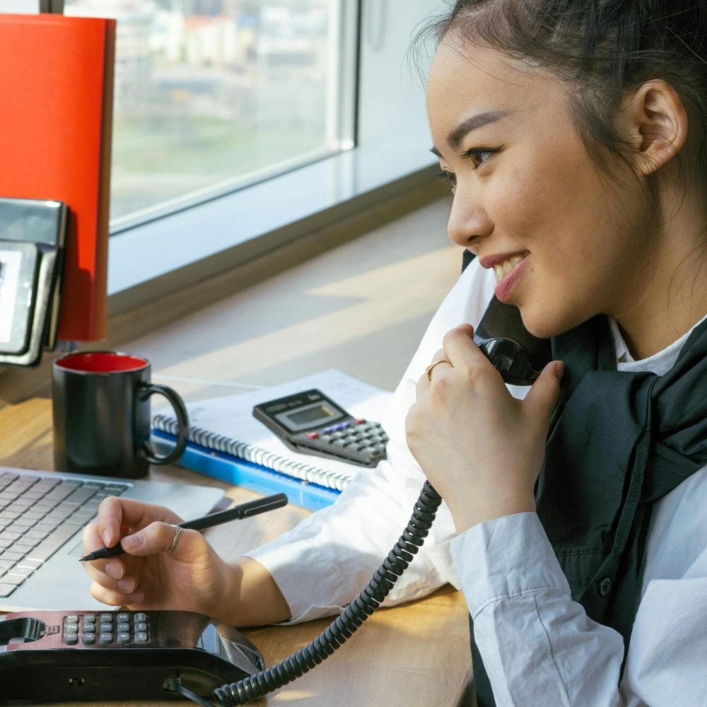 Filipino woman working at desk, multitasking with a smile.